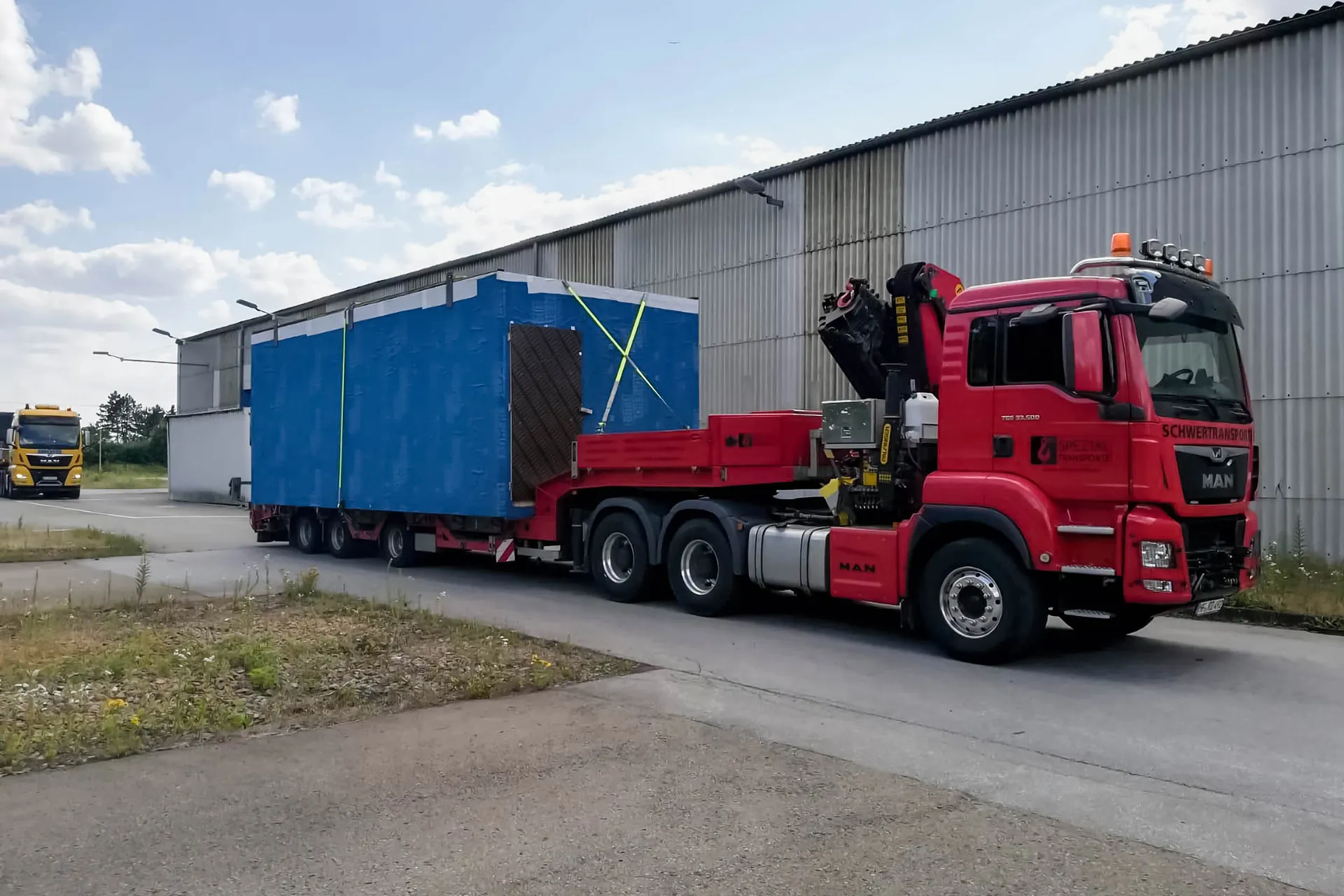 Ein Spezialtransporter lädt per Ladekran Container auf die Ladefläche