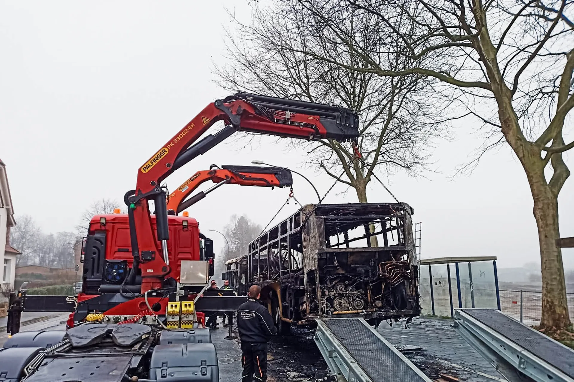 Bergung eines ausgebrannten Busses mit Ladekränen von Spezialtransportern