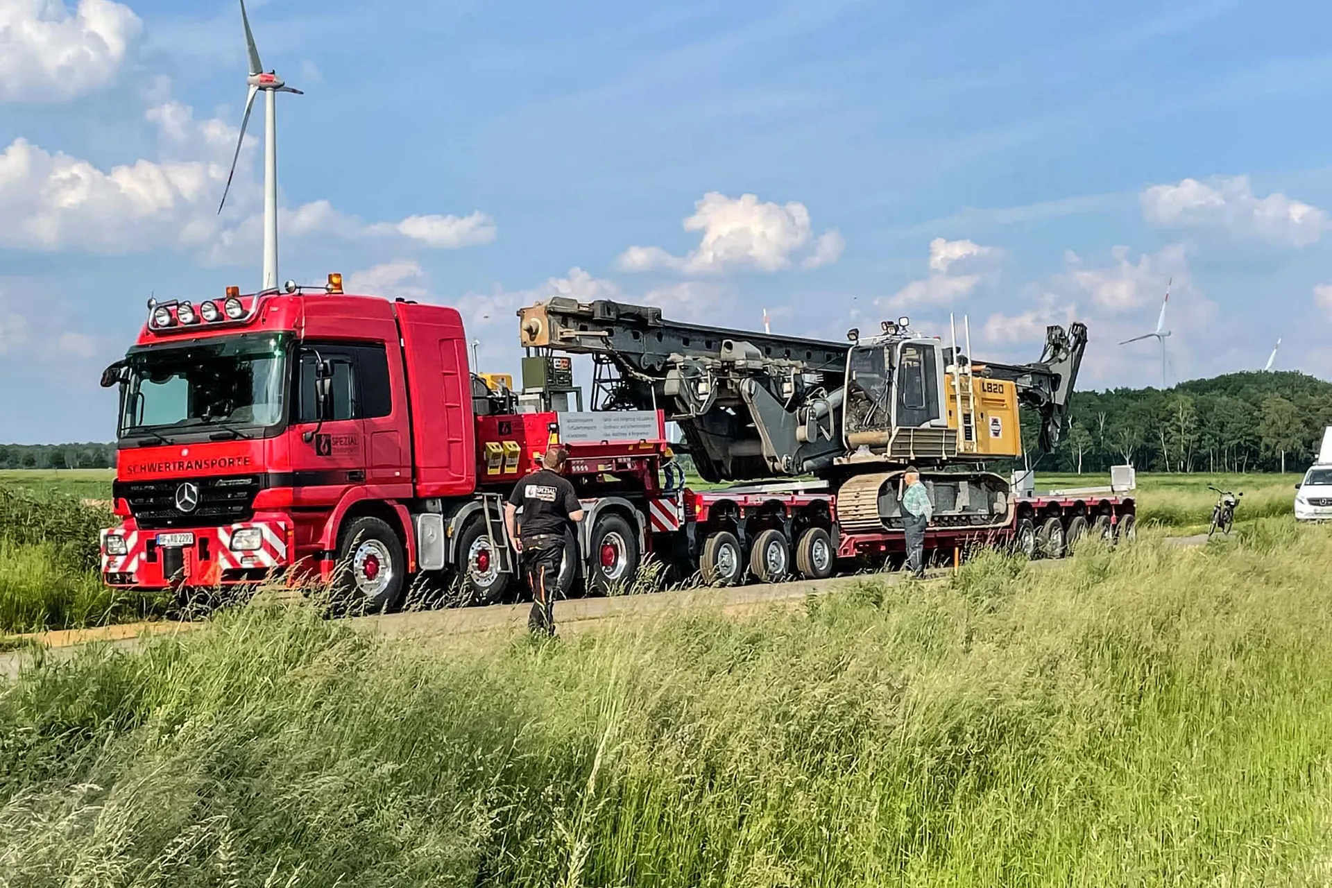 Ein Spezialtransporter der in einem Hafen per Kran ein schweres Element aufgeladen bekommt