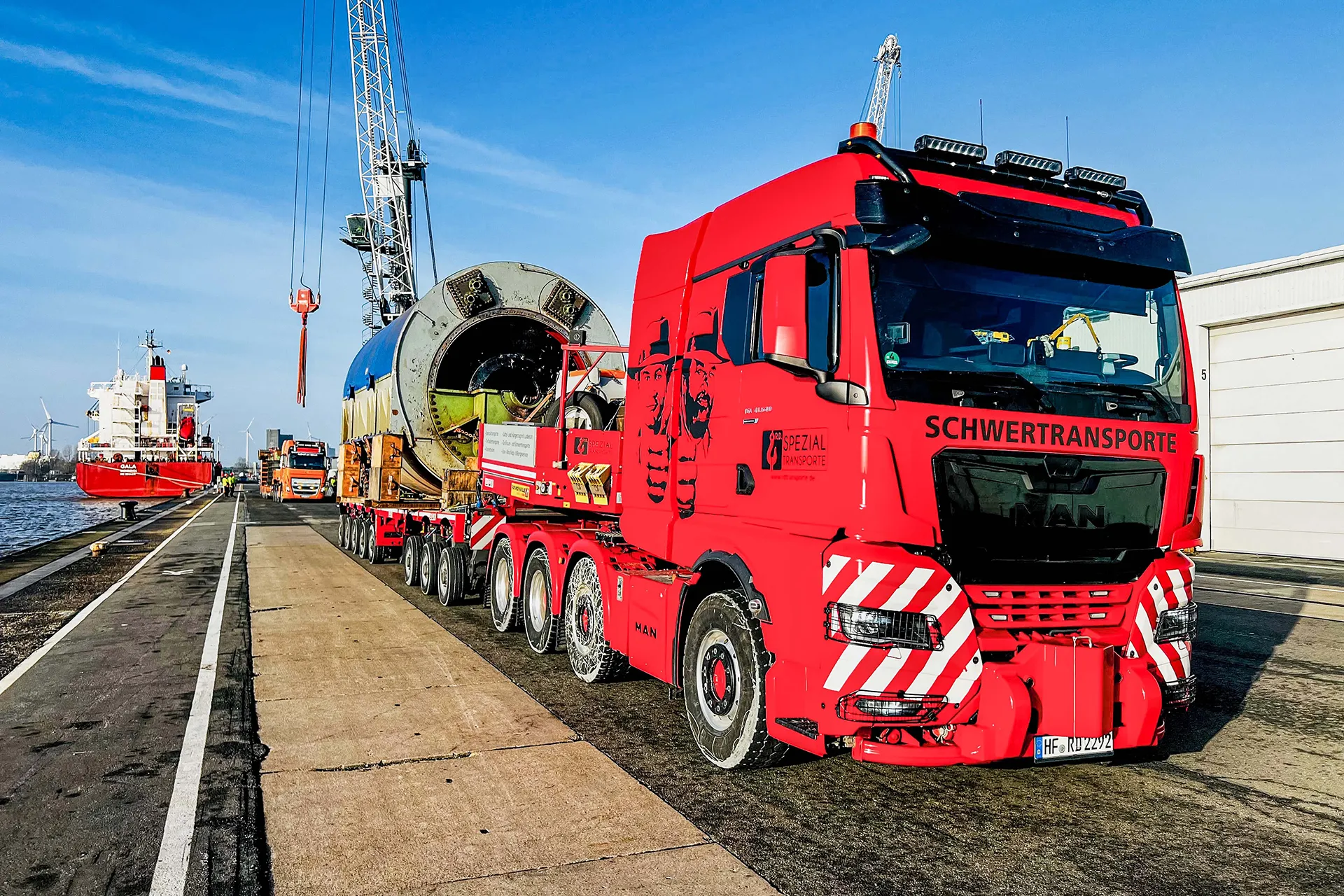 Zwei Schwertransporter, die per Kran ein großes Silo Element verladen