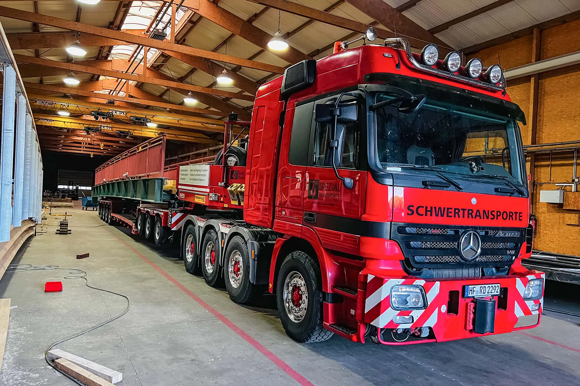 Ein Kran hebt ein schweres Maschinenbauteil auf einen Spezialtransporter