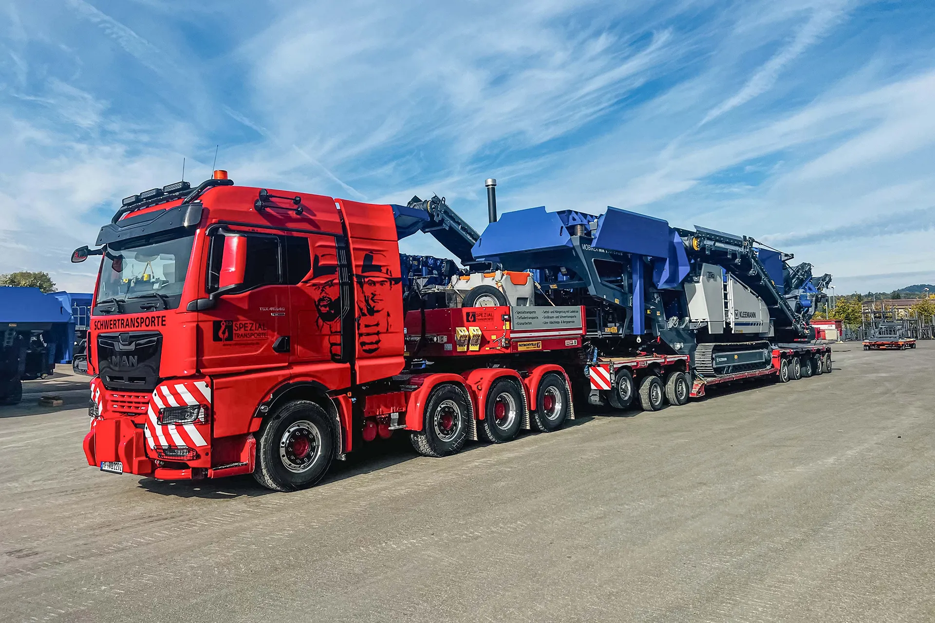 Ein Schwertransport in einer engen Kurve mit Lotsenfahrzeugen