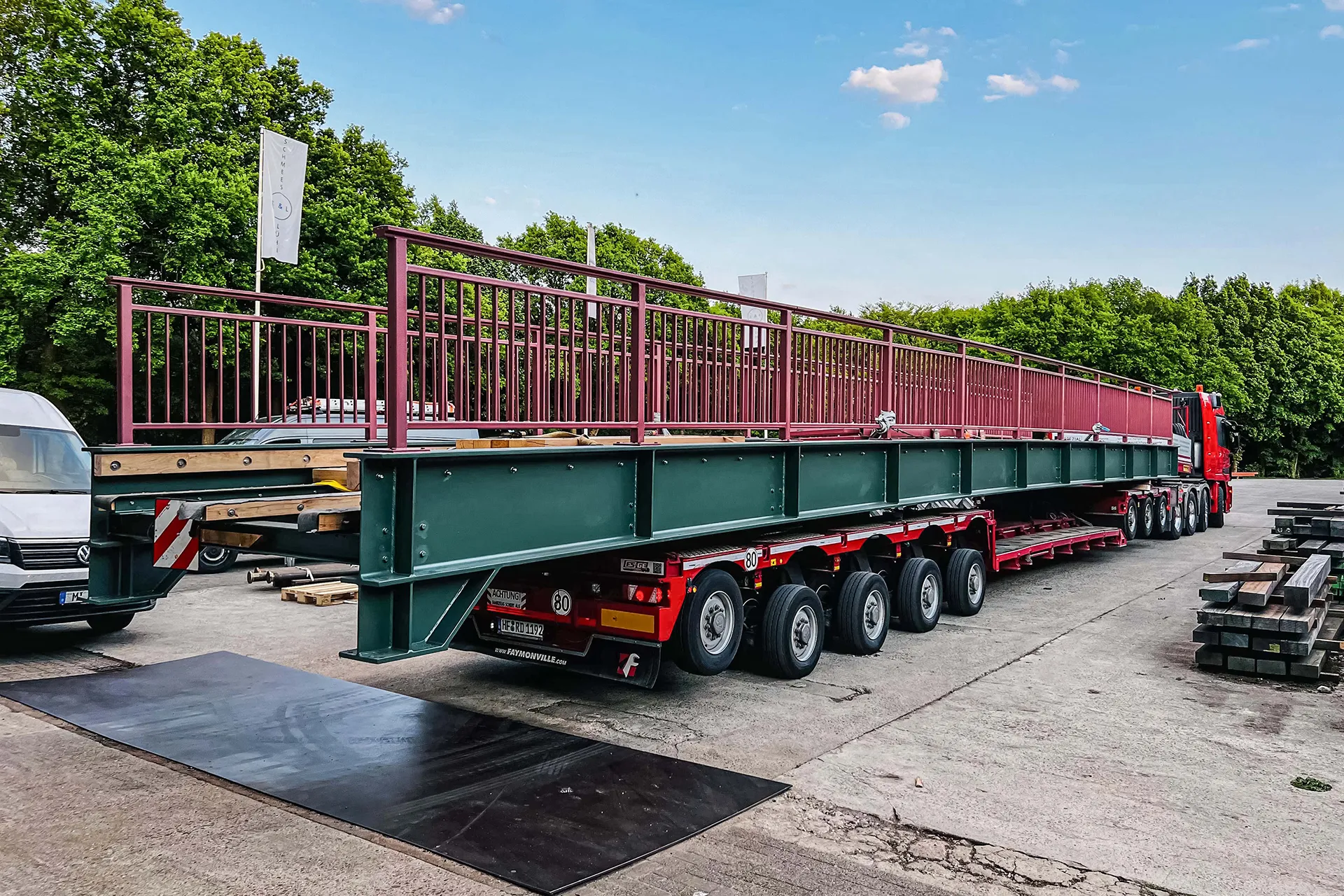 Schwertransport in einer Stadt, umgeben von Sicherheitsfahrzeugen